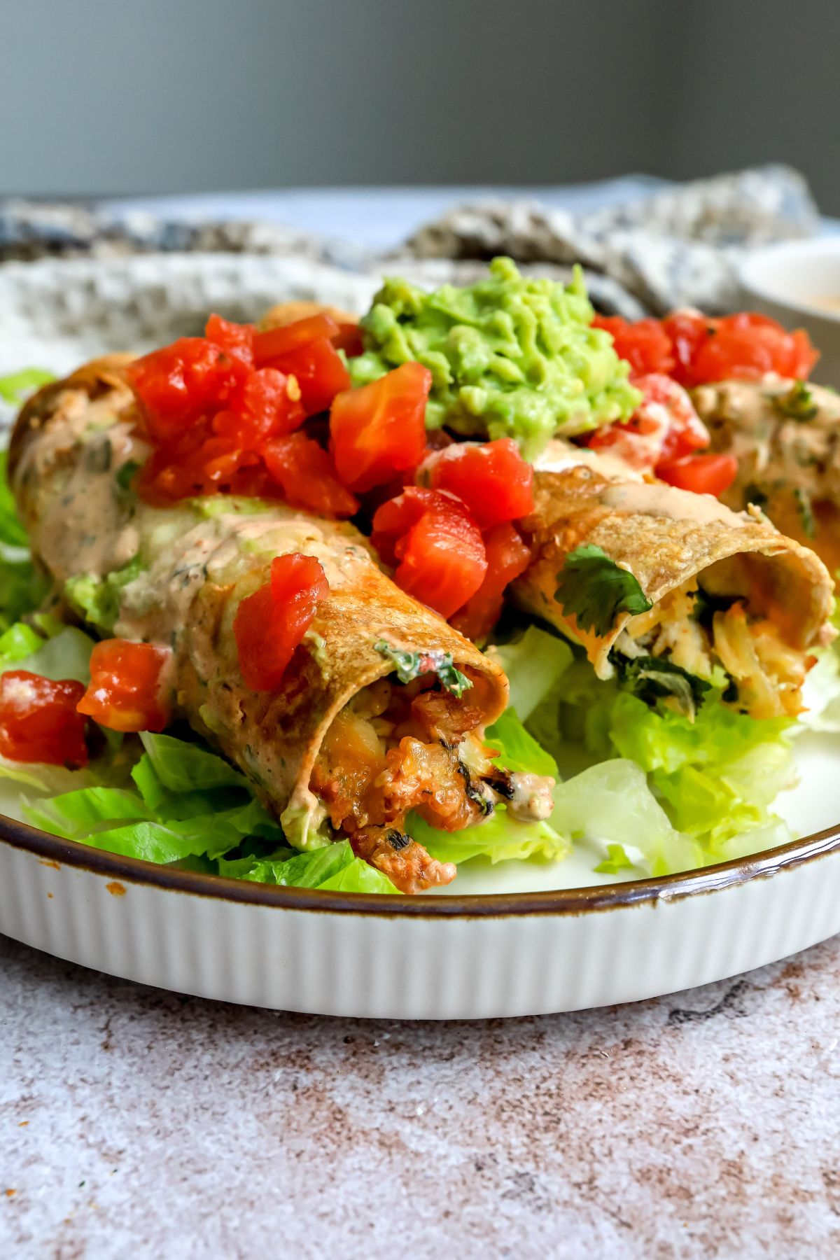 Baked Chicken Taquitos on a plate with toppings.