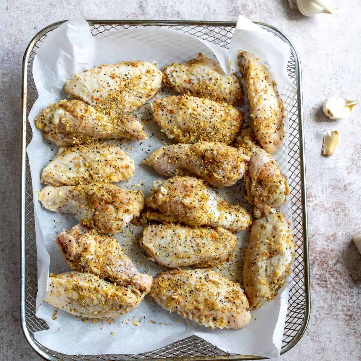 Steps to make Lemon Pepper Wings in an air-fryer basket with parchment. 