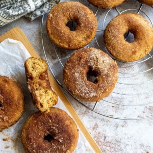 Baked Apple Cider Donuts on a cutting board with parchment paper.