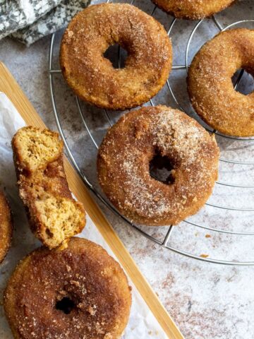 Baked Apple Cider Donuts on a cutting board with parchment paper.