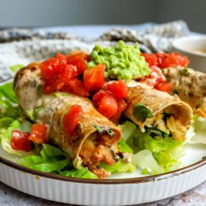 Baked Chicken Taquitos on a plate with toppings.