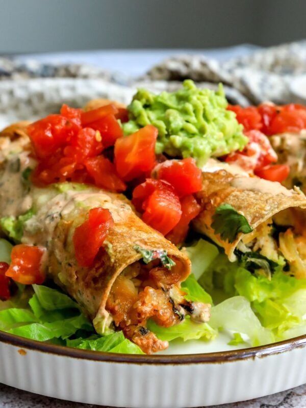 Baked Chicken Taquitos on a plate with toppings.