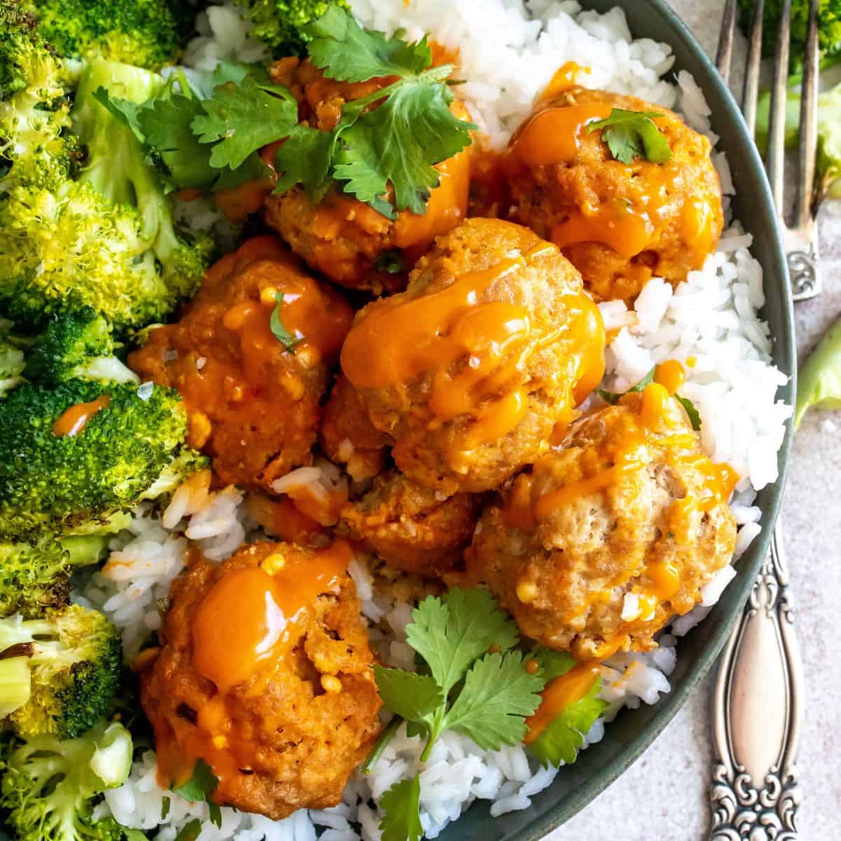 Buffalo meatballs in a bowl on top of rice and a side of broccoli.