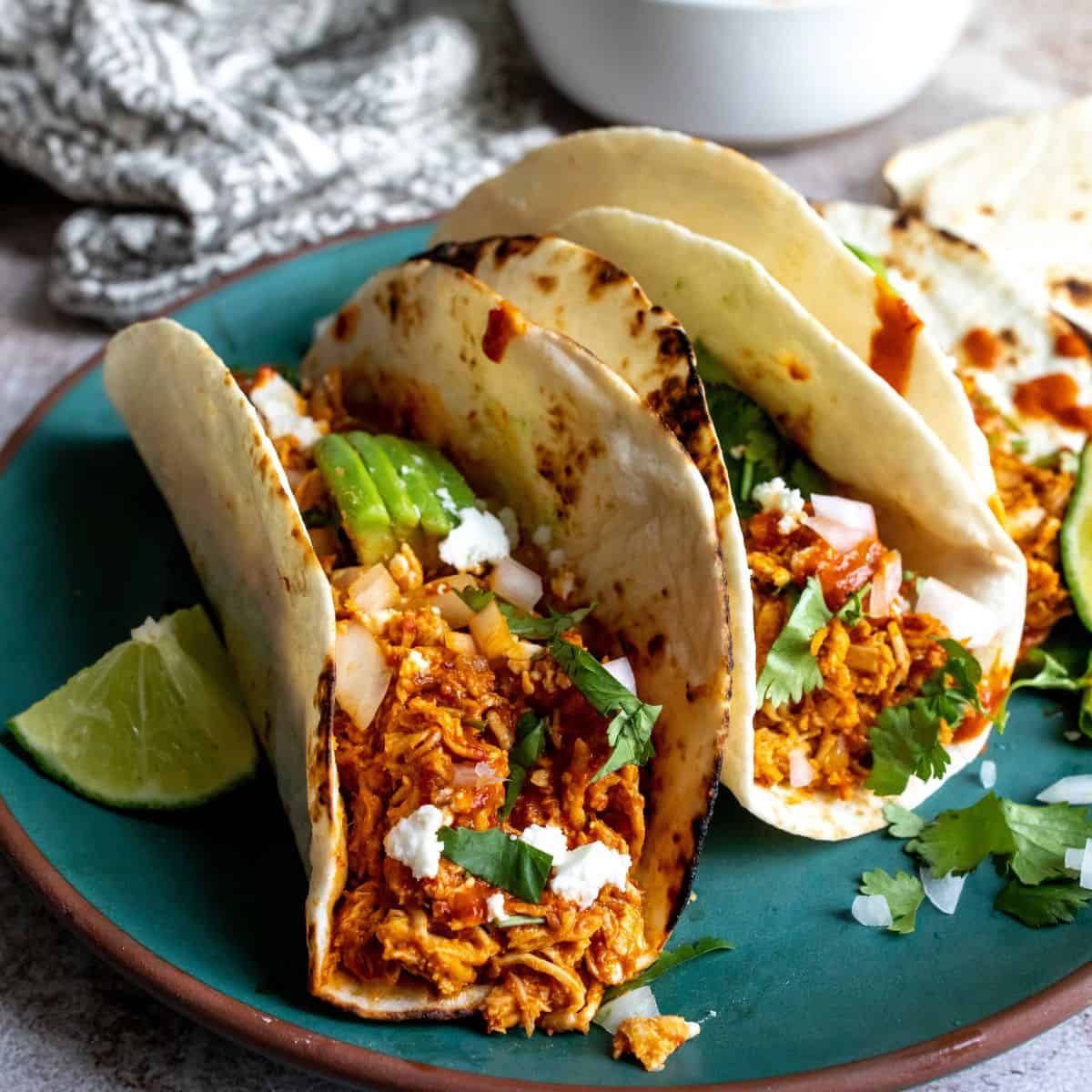 Tacos up close on a green plate with toppings. 