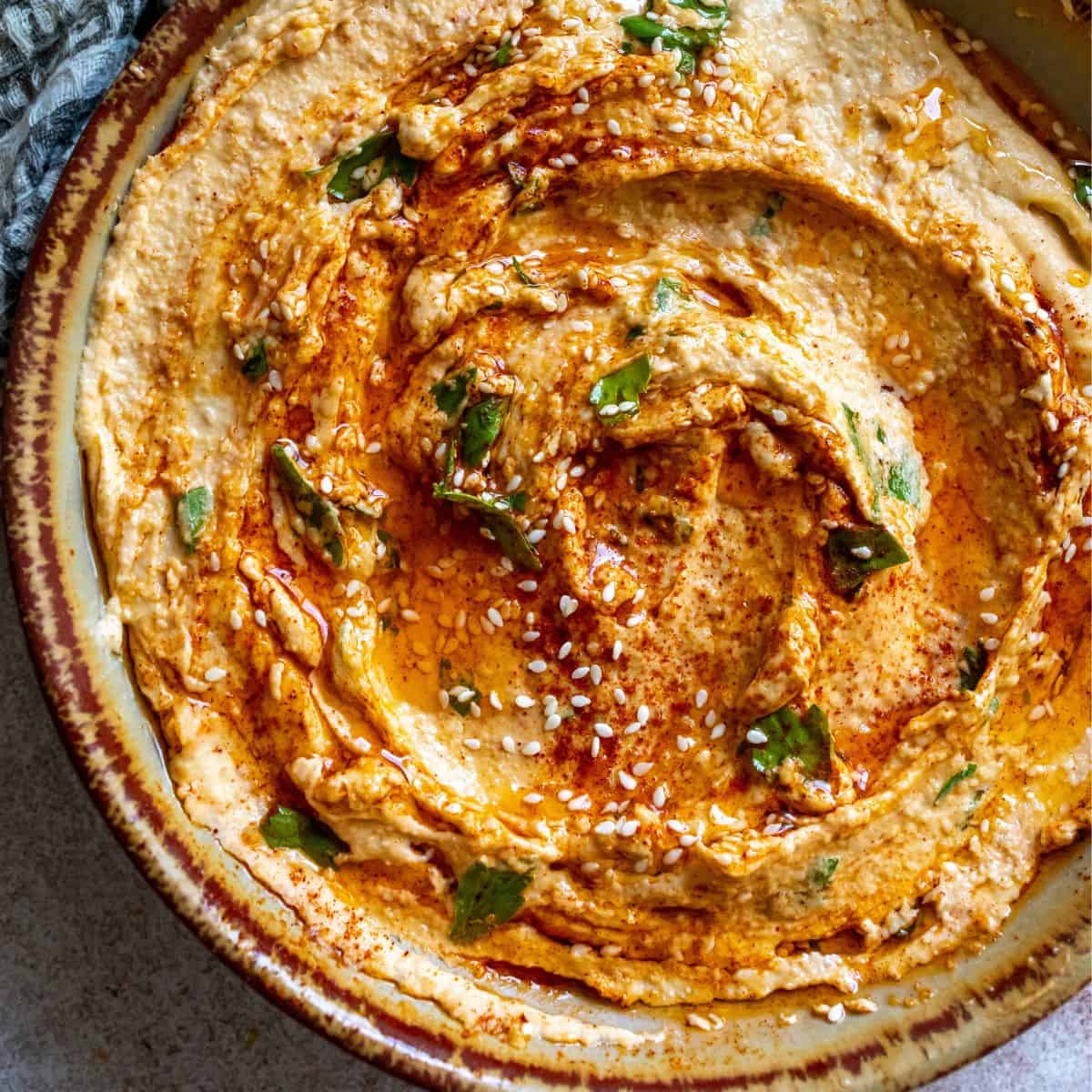 Creamy Hummus Recipe up close in a bowl with sesame seeds.
