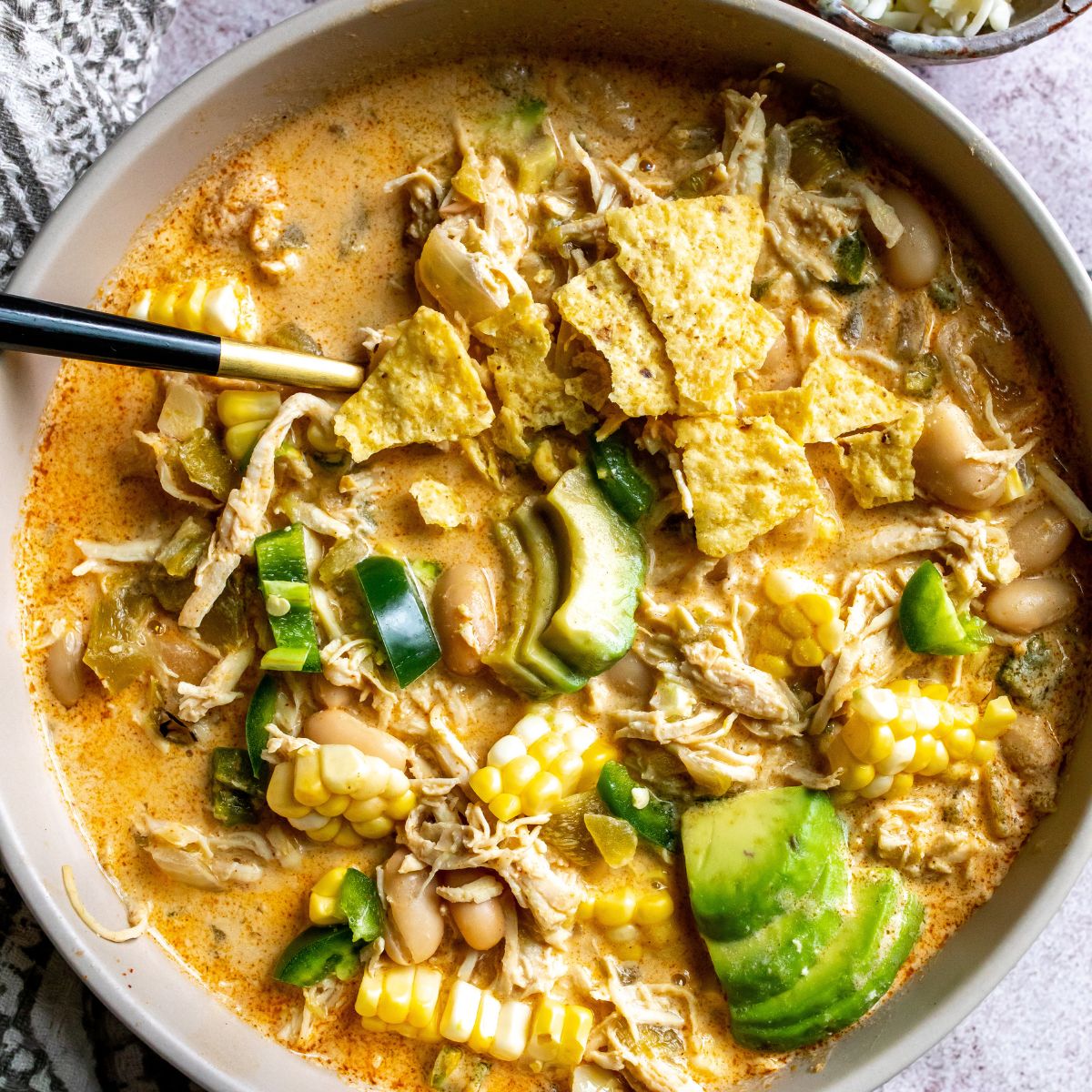 White Bean Chili With Chicken in a bowl with avocado and tortilla chips. 