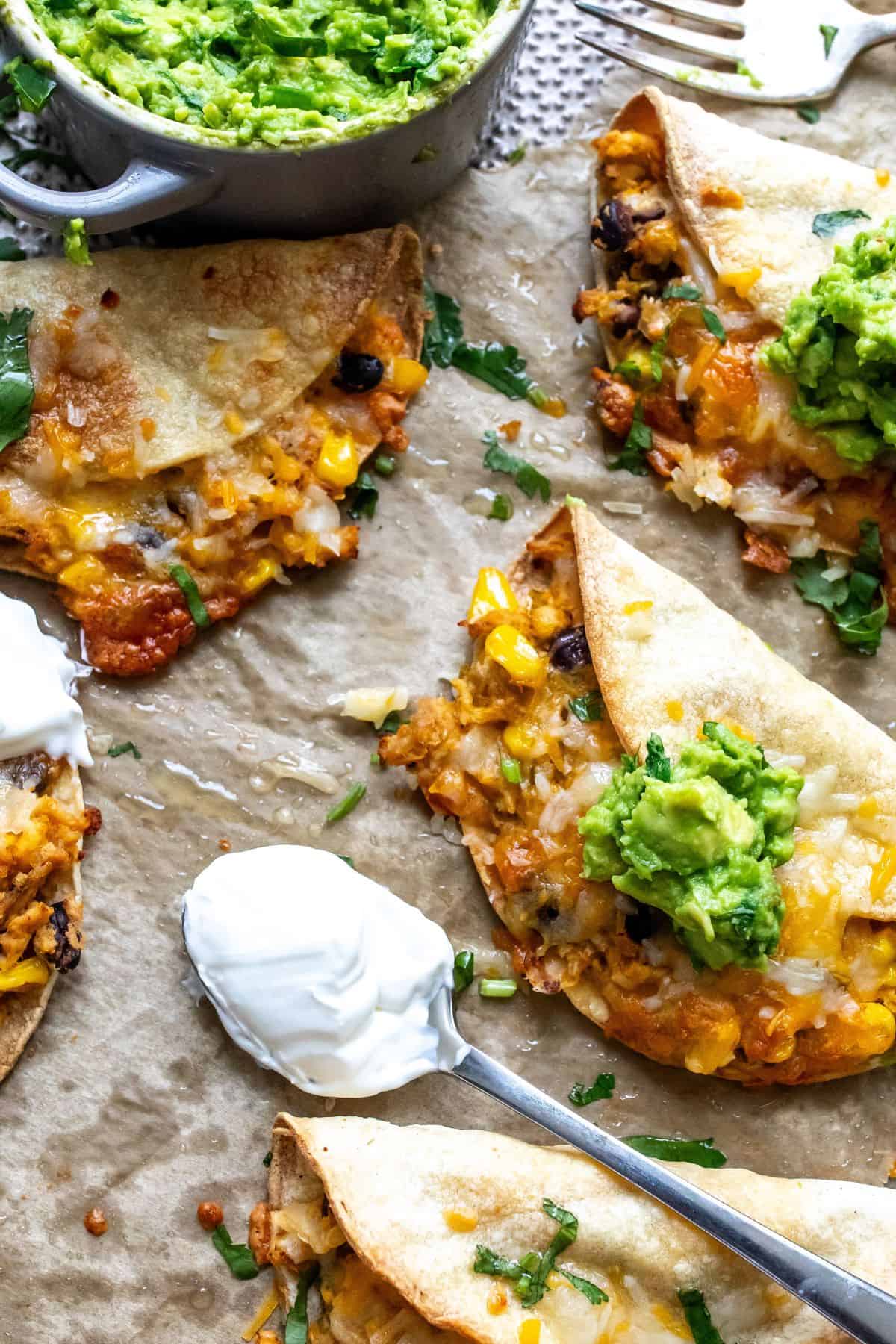 Crispy Chicken Tacos on a baking sheet with sour cream.