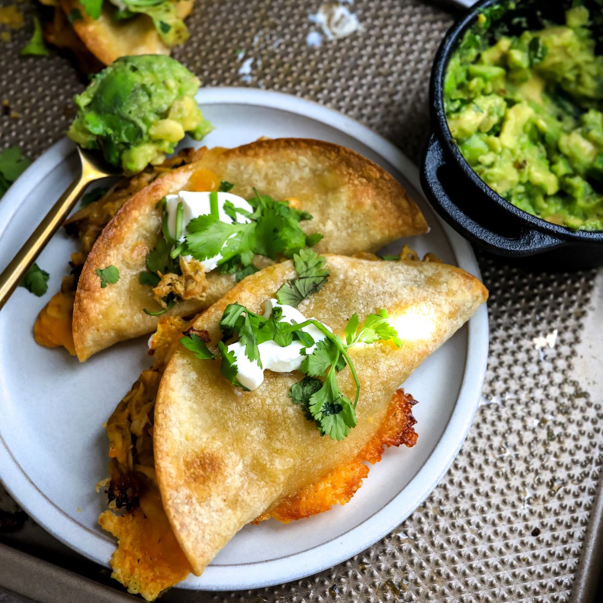 Crispy Chicken tacos on a white plate with avocado. 