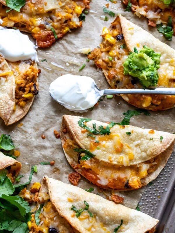 Crispy Chicken Tacos on a baking sheet with guacamole.