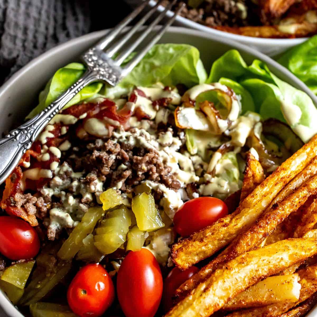 Up close photo of cheeseburger bowl in a white bowl with a silver fork. 