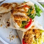 Crispy Chicken Wraps on a white plate with lettuce and tomato.
