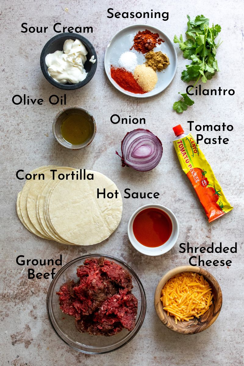 ingredients for tacos on a grey counter in clear and wooden bowls.