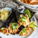 Hand rolls on a white plate with avocado.