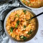 Shrimp bisque in a grey bowl with a black spoon.