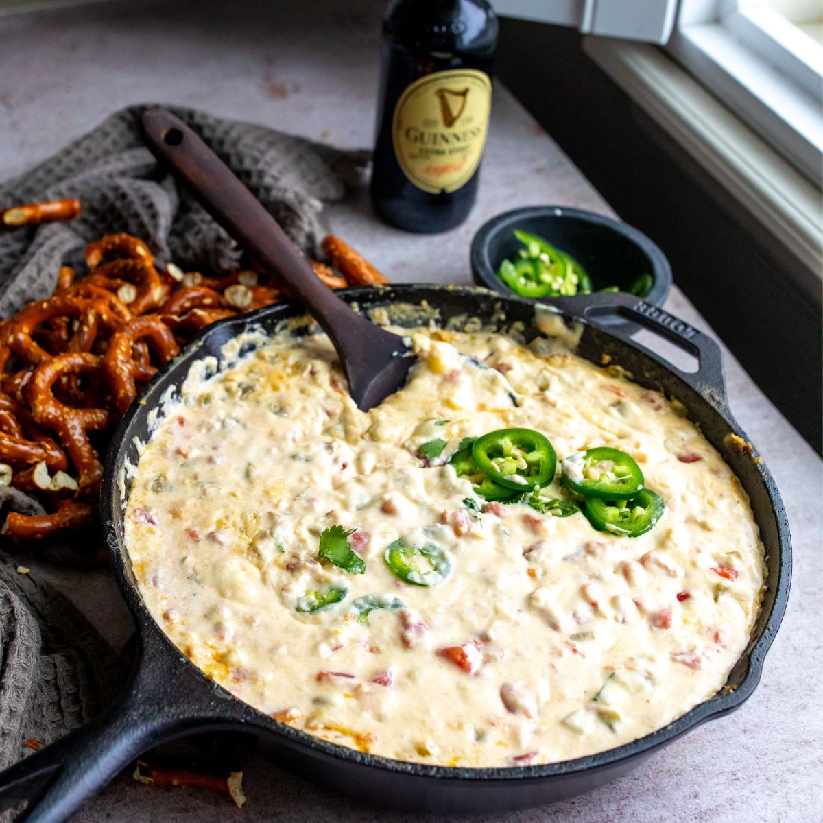Smoked queso with jalapeño  on top and a spoon. 