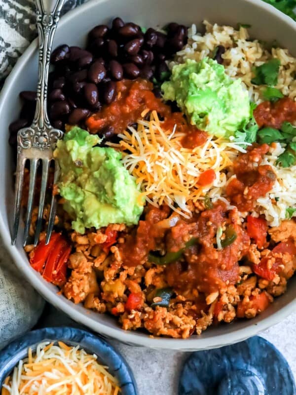 Rice, beans, taco meat in a grey bowl with a silver fork.