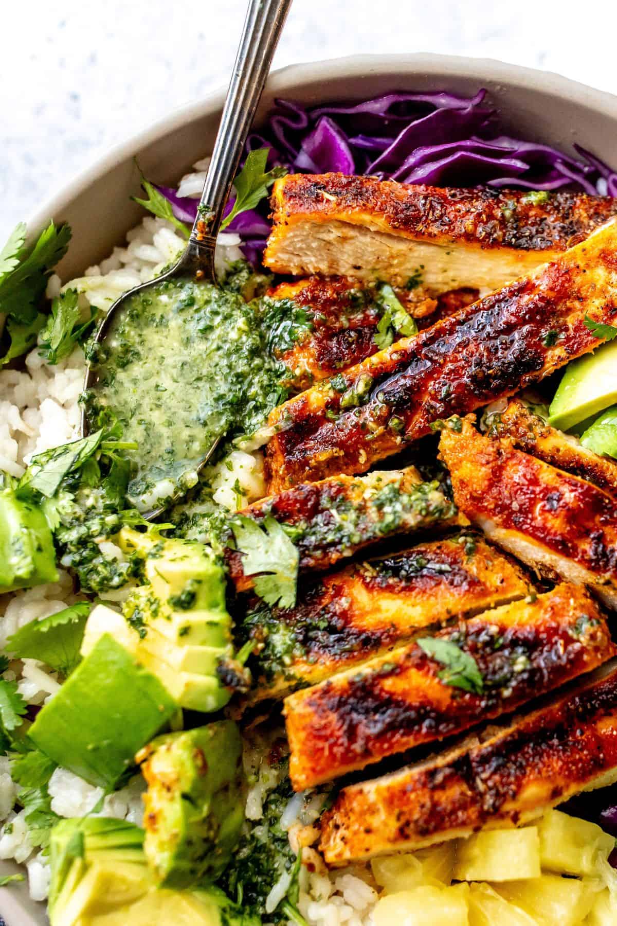 Blacked chicken in a bowl with cilantro lime dressing up close with a spoon.