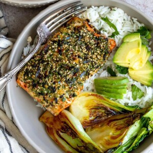 Salmon on white rice with green veggies in a bowl.