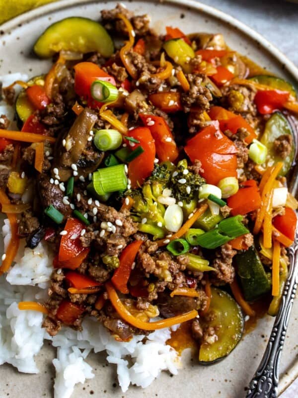 Ground beef stir fry with veggies on a plate over rice.