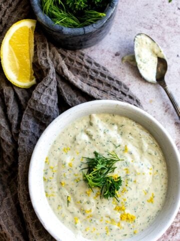 Dressing in a white bowl with lemon.