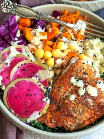 bowl with bright veggies and salmon on top up close with a fork.