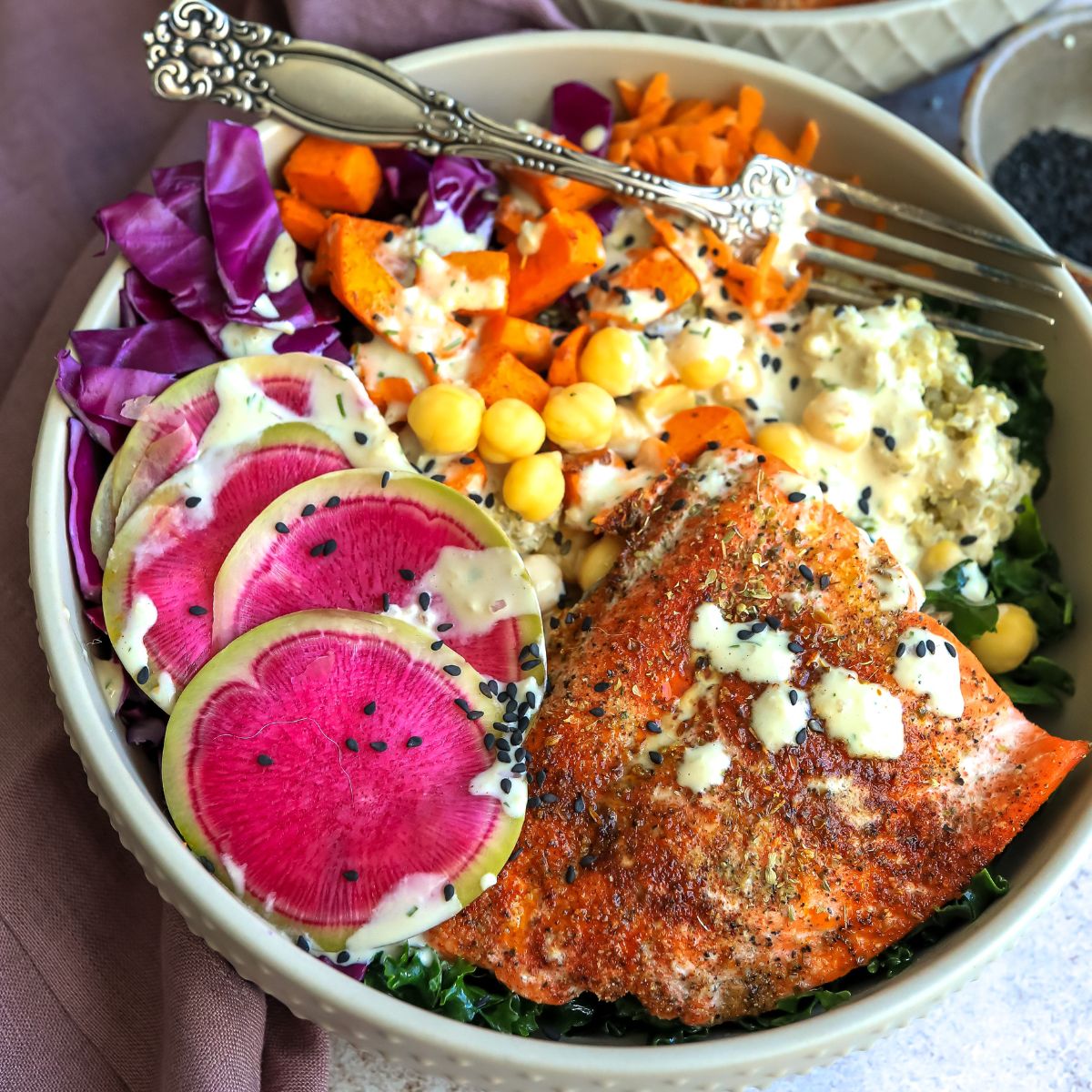 bowl with bright veggies and salmon on top up close with a fork.