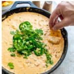 Smoked Queso in a black cast iron with jalapeños on top.