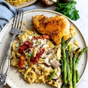 Chicken and orzo on a plate with asparagus.