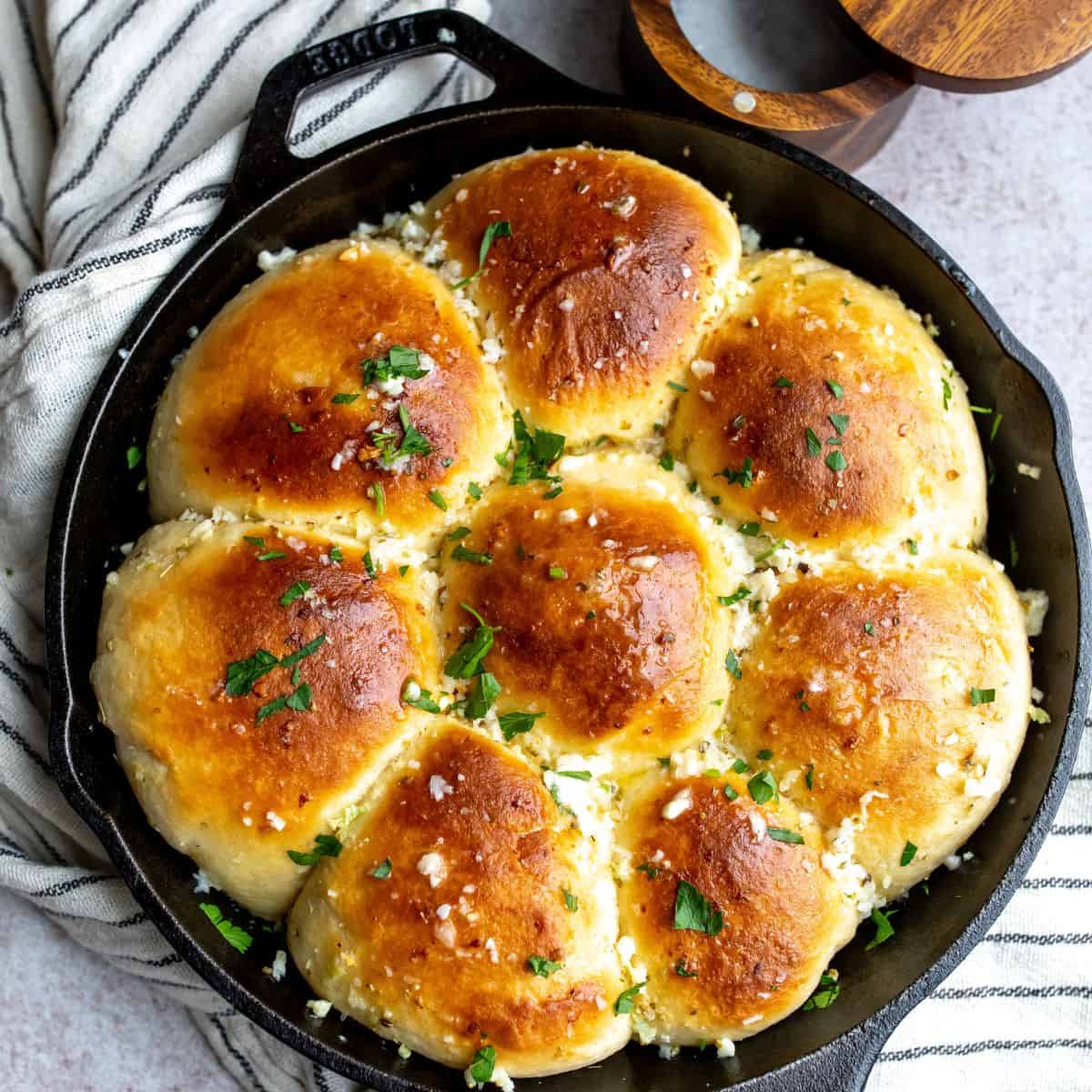 Buttered rolls in a cast iron skillet with chopped parsley. 