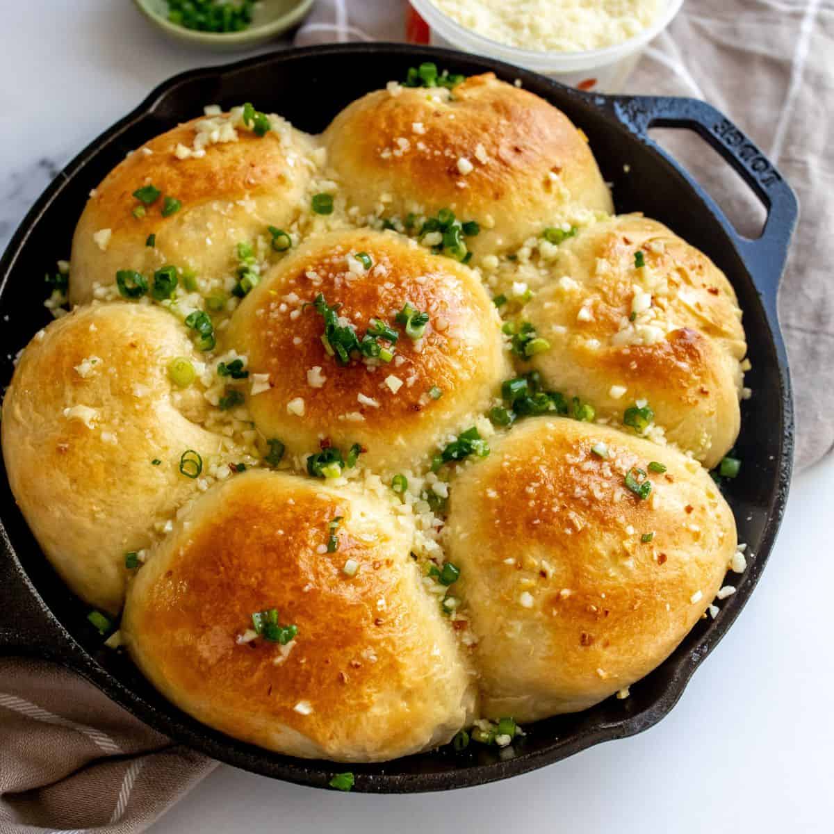 Garlic rolls in a cast iron with chives on top.