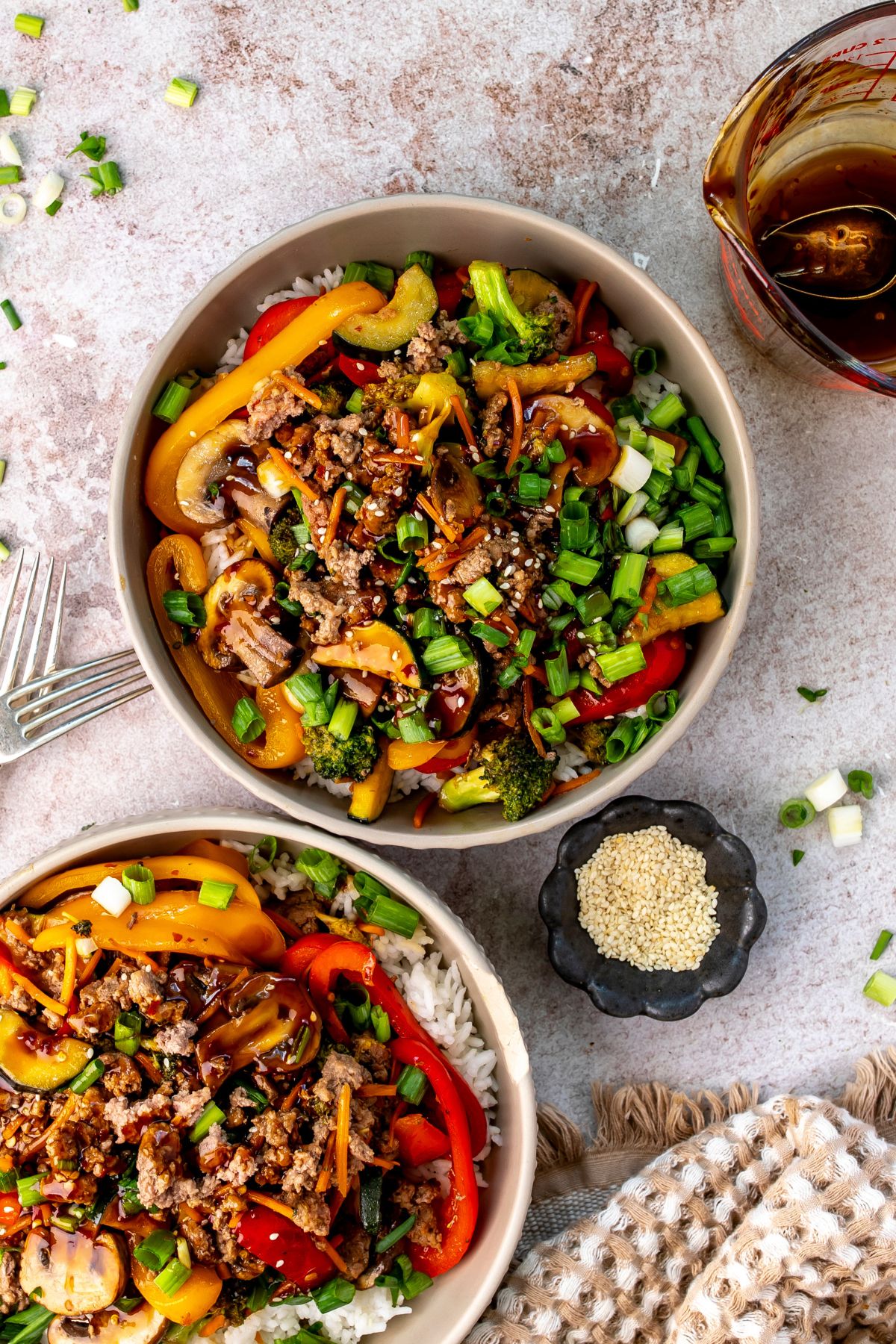 White bowls with ground beef stir fry in it and onions on the side.