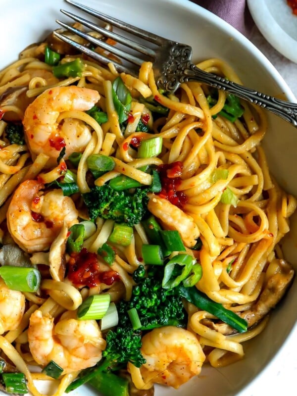 Noodles in a white bowl with shrimp and a fork.