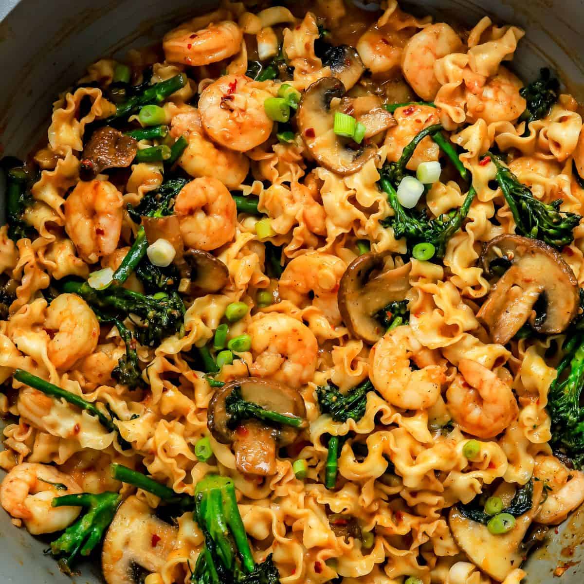 miso noodles in a skillet with broccolini and shrimp.