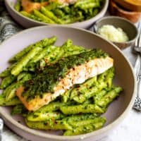 Pesto pasta with salmon on top and parmesan.