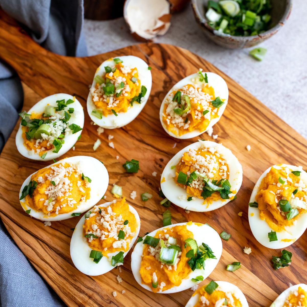 Deviled eggs on a cutting board with scallions. 