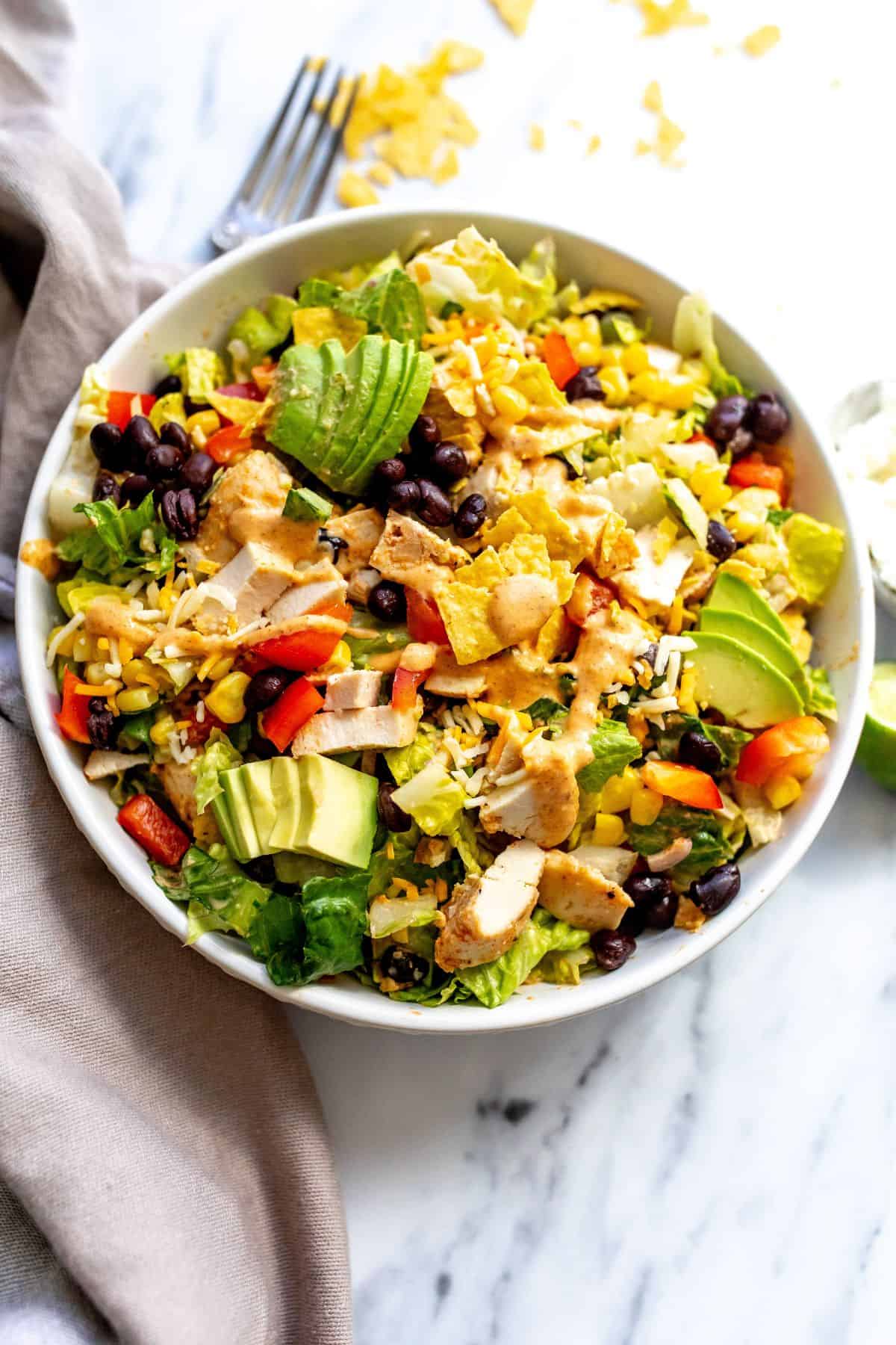 Spicy Southwest Salad in a white bowl on a counter with a towel to the side.