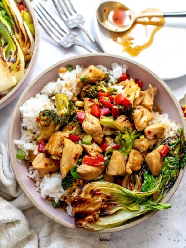 Teriyaki Chicken Rice Bowls on a counter with a plate and a spoon on the side.