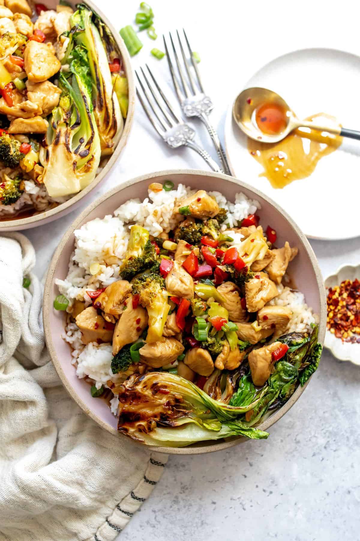 Teriyaki Chicken Rice Bowls on a counter with a plate and a spoon on the side.