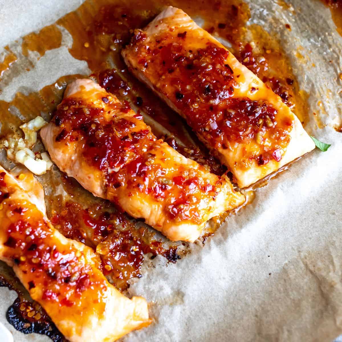 Salmon with sauce up close on a baking sheet. 