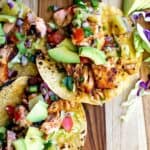 Tacos on a cutting board with blackened salmon.