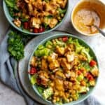 Two bowls with salad, tomatoes and chicken in it.