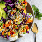 Salad rolls in a bowl with a spoon and cilantro.