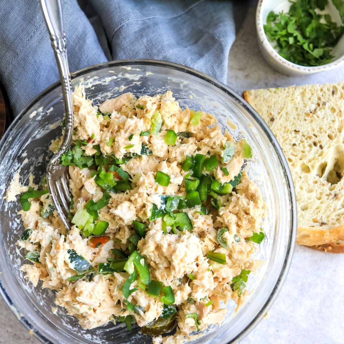 Tuna in a clear bowl with jalapeño and bread.