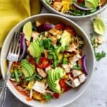 Two grey bowls with thai mango salad and a fork in the bowl on the table.