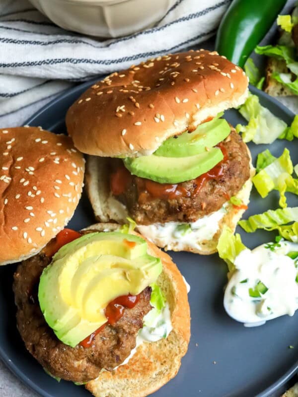 Two burgers on a plate with sesame buns.