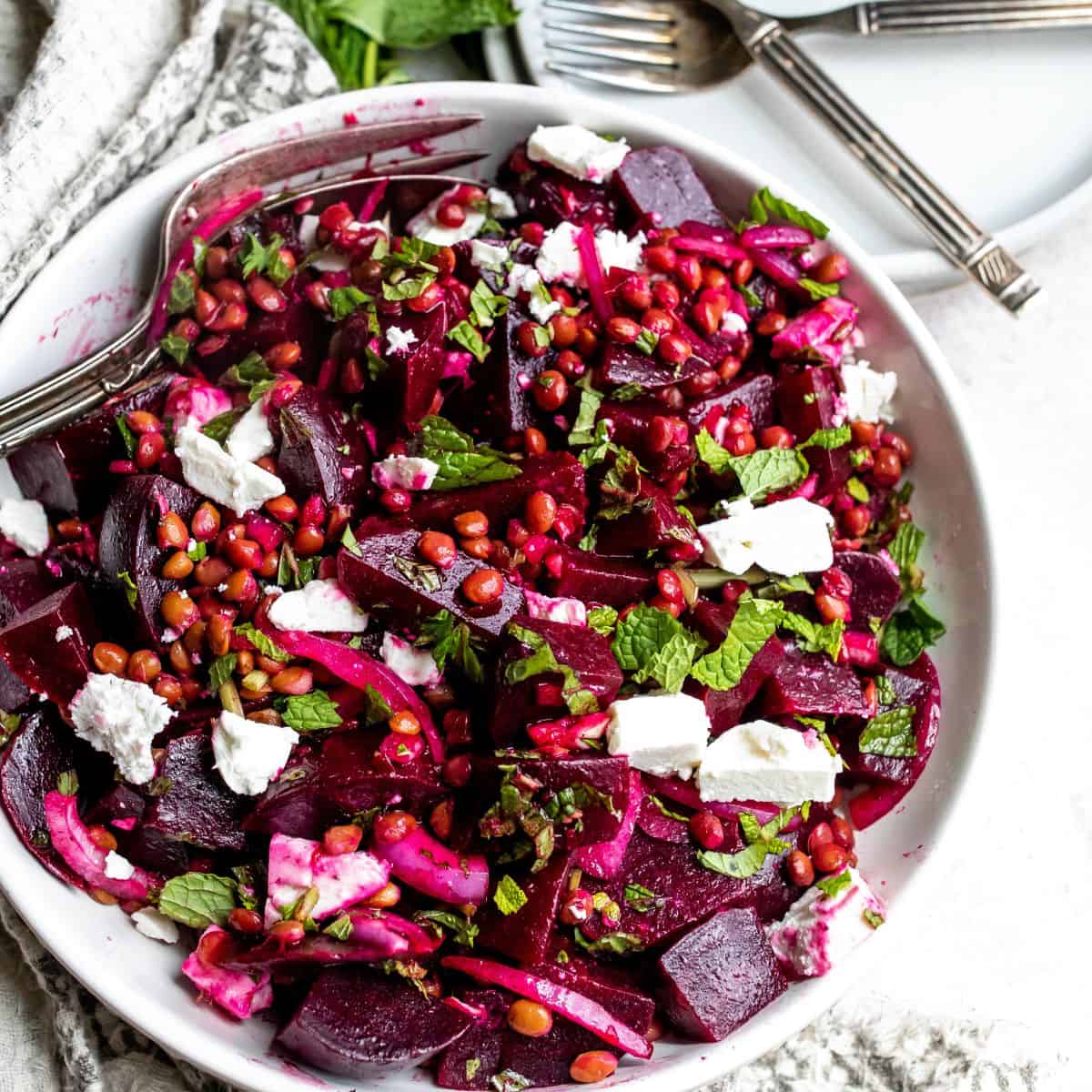 White bowl with beets and mint, up close in a wooden bowl. 