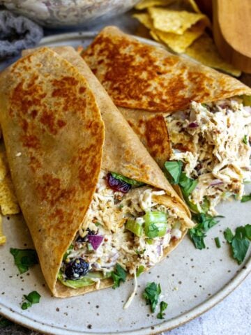 Wraps with chicken salad on a plate with chips.