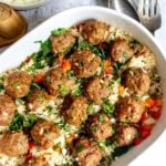 Meatballs and rice in an oval casserole dish on a countertop.