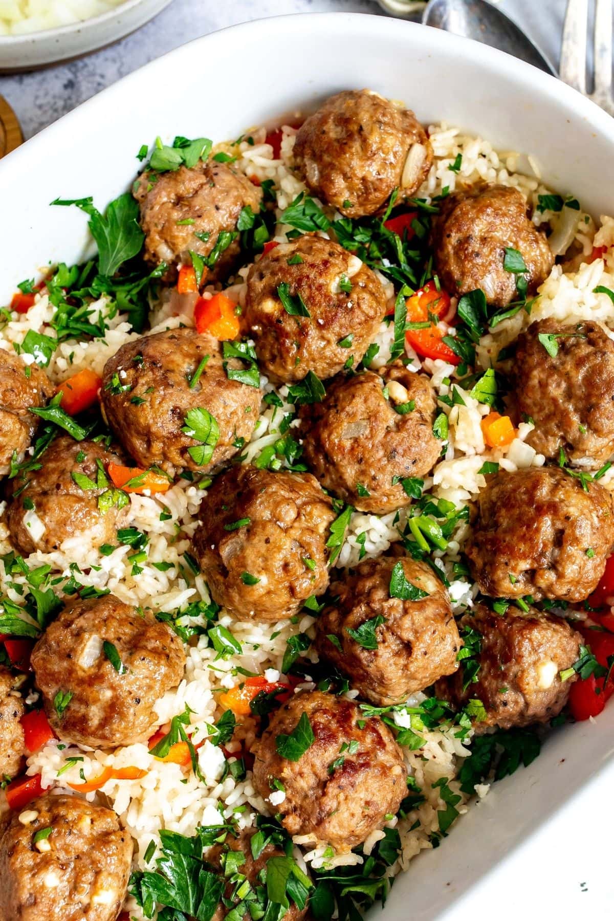 The meatballs and rice in a white casserole dish after baking.
