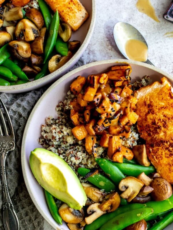 Two bowls with salmon, fresh veggies and quinoa.